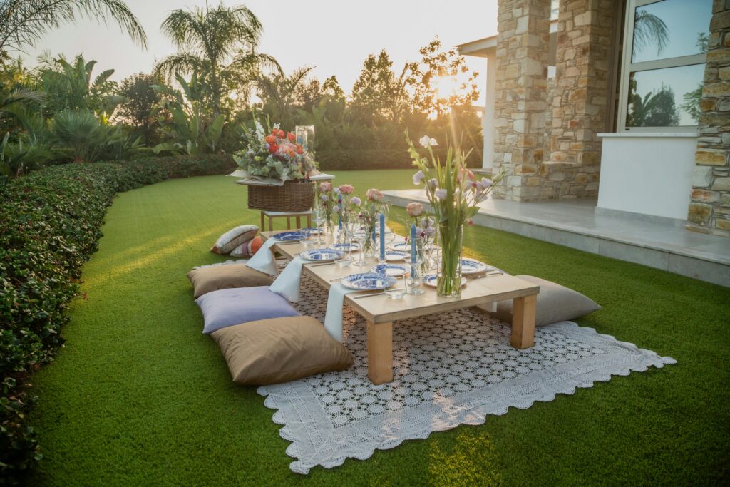 A beautifully set outdoor garden table with flowers and cushions at sunset.